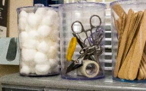  Three jars of medical supplies on a shelf.